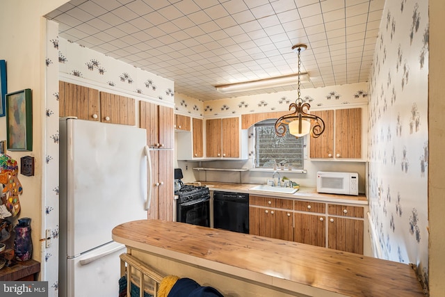 kitchen featuring decorative light fixtures, brown cabinets, black appliances, and a sink