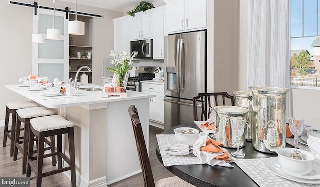 kitchen featuring a sink, backsplash, a barn door, appliances with stainless steel finishes, and light countertops