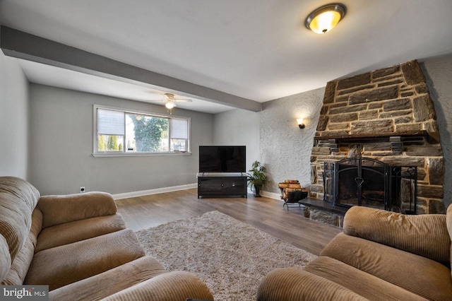 living room featuring ceiling fan, a fireplace, baseboards, and wood finished floors