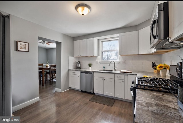 kitchen with dark wood finished floors, stainless steel appliances, white cabinetry, a ceiling fan, and a sink