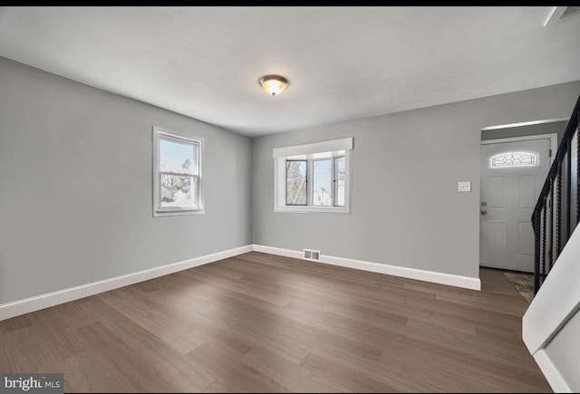 foyer entrance with visible vents, stairs, baseboards, and wood finished floors