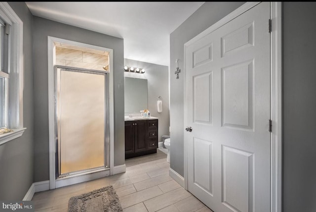 bathroom featuring toilet, a stall shower, wood finished floors, baseboards, and vanity