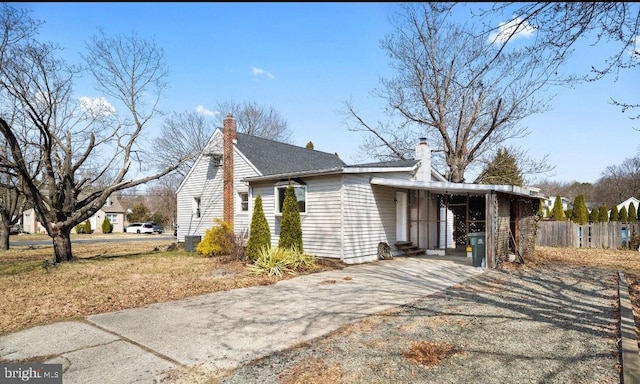 view of side of home featuring central AC unit, a chimney, and fence