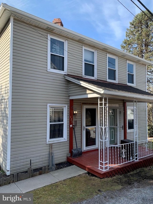 view of front facade with covered porch and a chimney