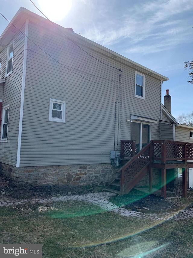 rear view of house featuring stairs and a wooden deck