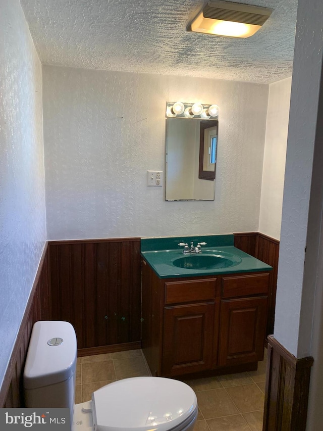 bathroom with wooden walls, toilet, and wainscoting