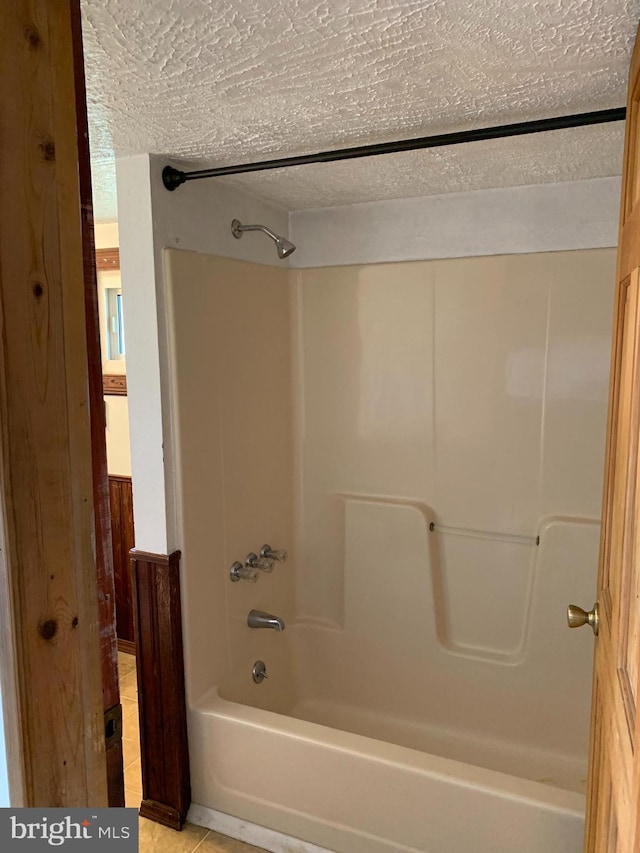 full bathroom featuring shower / bathing tub combination, a textured ceiling, and tile patterned flooring