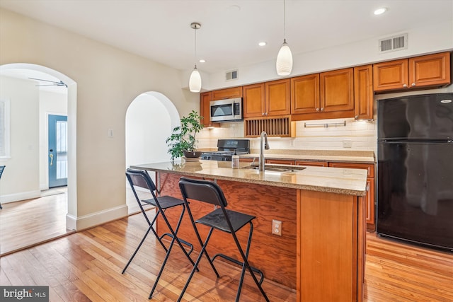 kitchen featuring black appliances, visible vents, arched walkways, and a sink