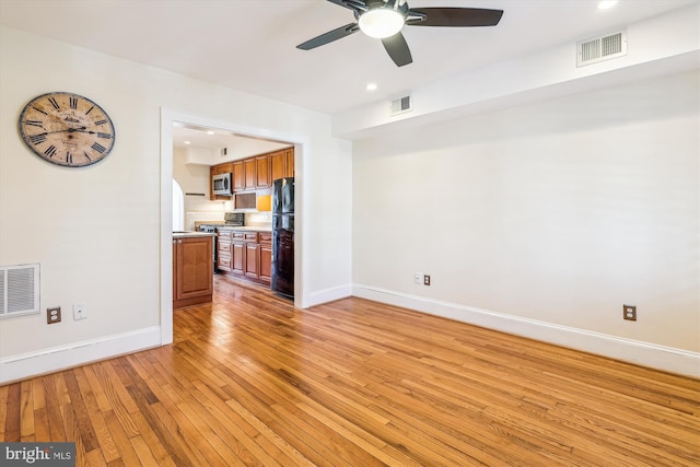 unfurnished living room with light wood-type flooring, visible vents, and baseboards