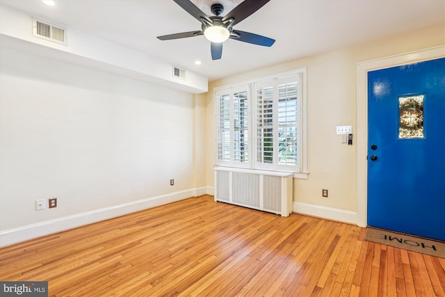 foyer with radiator heating unit, baseboards, visible vents, and wood-type flooring