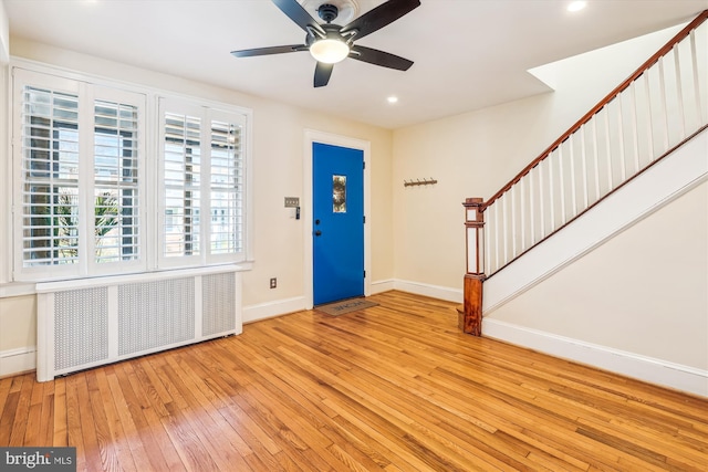 entrance foyer with a ceiling fan, hardwood / wood-style flooring, radiator heating unit, baseboards, and stairs