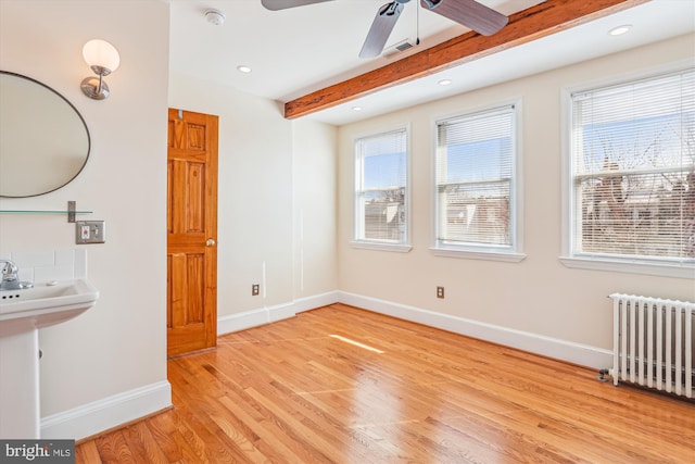 interior space featuring baseboards, beamed ceiling, light wood-type flooring, radiator heating unit, and recessed lighting