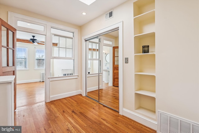 interior space featuring light wood-style flooring, radiator heating unit, baseboards, and visible vents