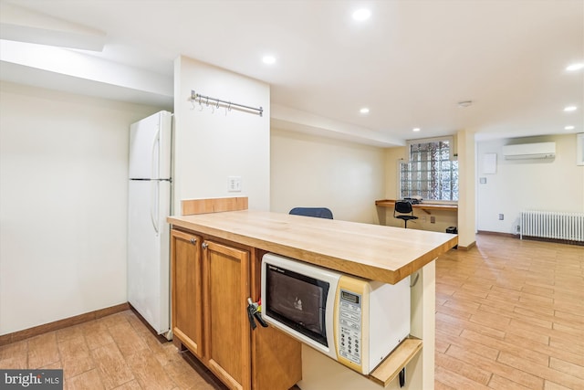 kitchen featuring butcher block countertops, light wood-style flooring, a wall mounted AC, radiator heating unit, and white appliances