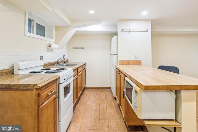 kitchen with white electric range, a sink, light wood-style floors, a peninsula, and a breakfast bar area