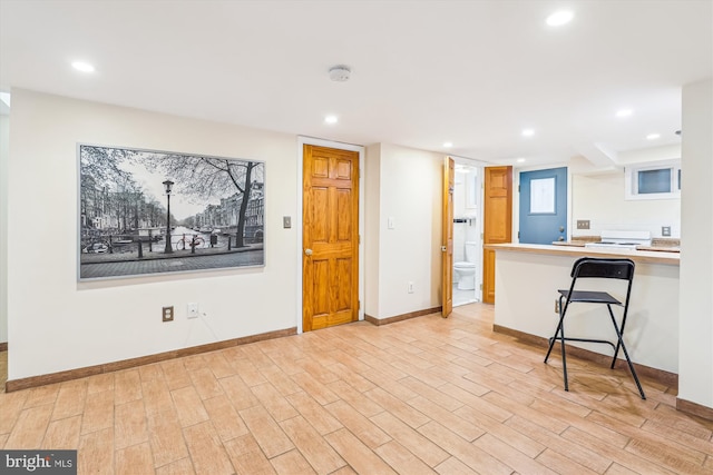 kitchen featuring recessed lighting, a peninsula, light wood-type flooring, and baseboards