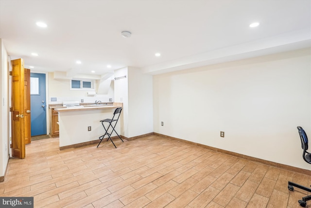 kitchen featuring recessed lighting, light wood-style flooring, a peninsula, and a breakfast bar area