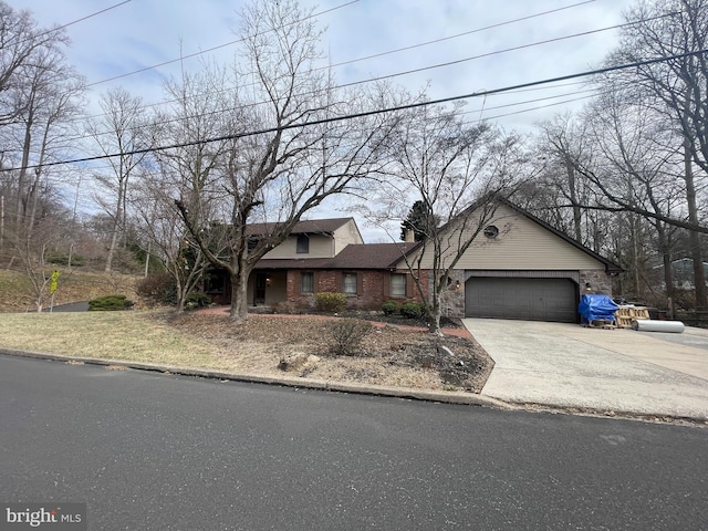 view of front of home featuring brick siding, an attached garage, concrete driveway, and a chimney