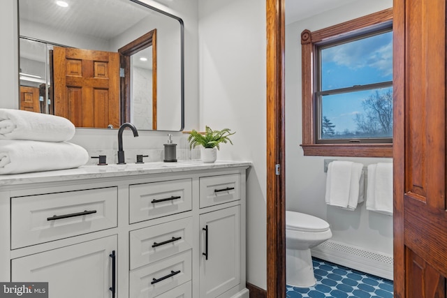 bathroom featuring baseboards, baseboard heating, toilet, and vanity