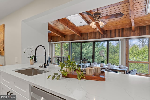 kitchen featuring a sink, wooden ceiling, a skylight, and beamed ceiling