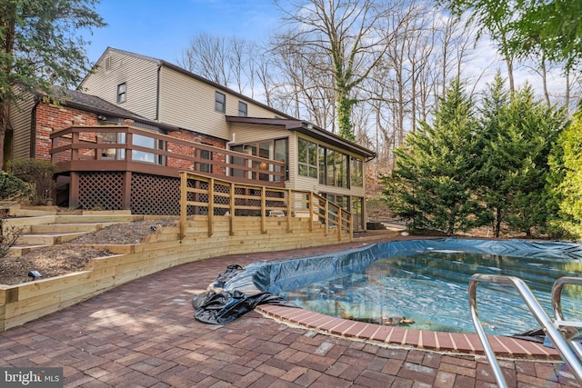 view of pool featuring a sunroom, a covered pool, a patio, stairway, and a deck