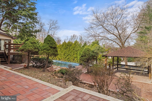 view of patio / terrace with stairs, a gazebo, a wooden deck, and a covered pool