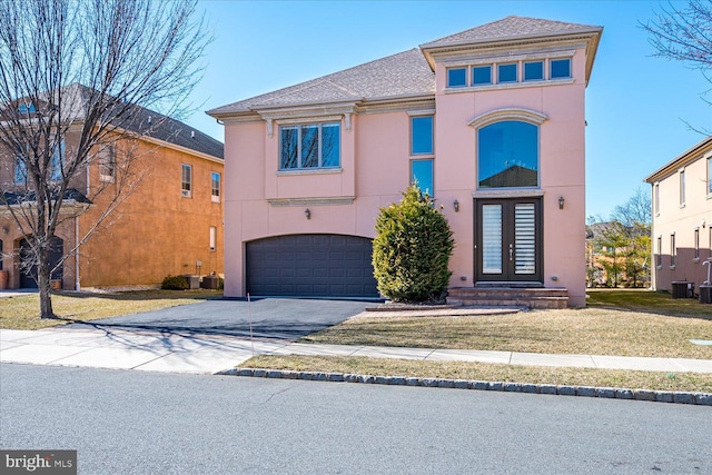 view of front of home featuring stucco siding, driveway, french doors, roof with shingles, and a garage