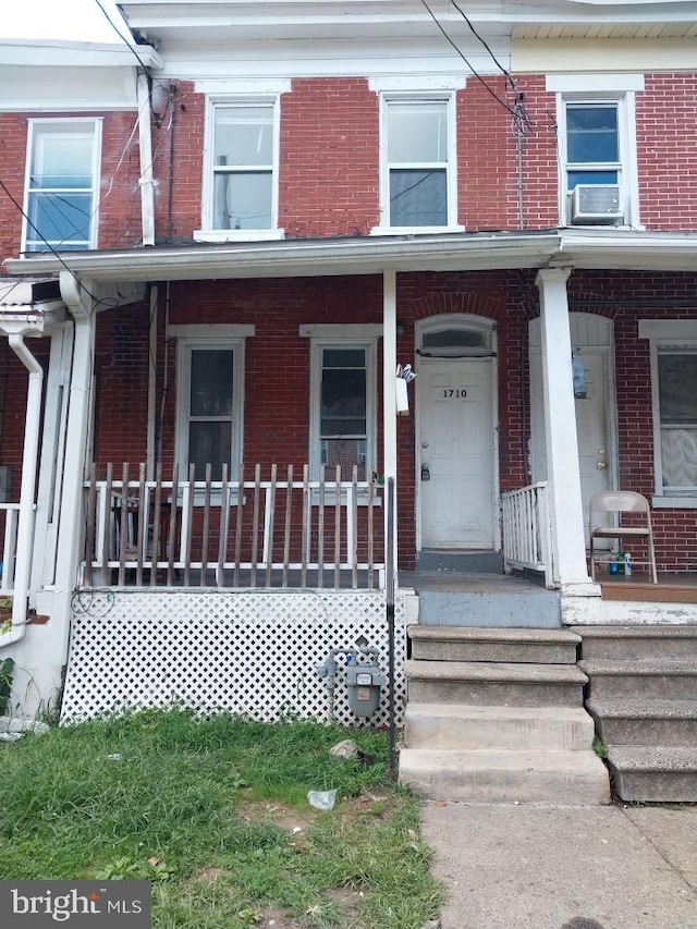 multi unit property with cooling unit, brick siding, and covered porch