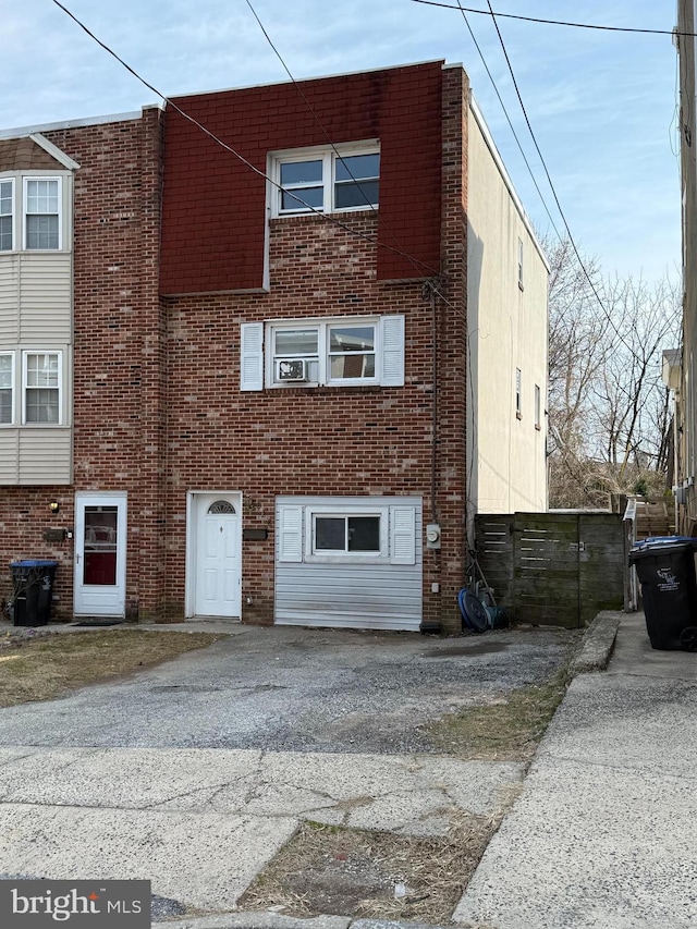 multi unit property with aphalt driveway, a garage, and brick siding