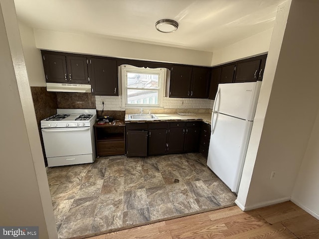 kitchen featuring backsplash, under cabinet range hood, light countertops, white appliances, and a sink