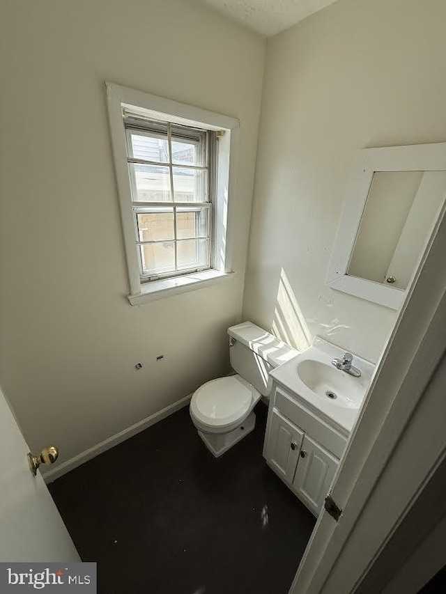 bathroom with toilet, vanity, and baseboards