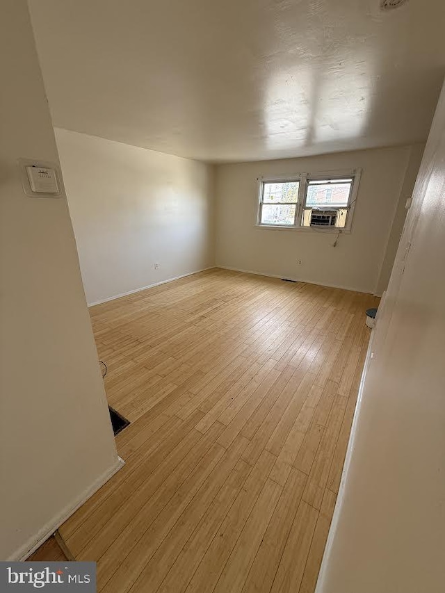 unfurnished room featuring cooling unit and light wood-style floors