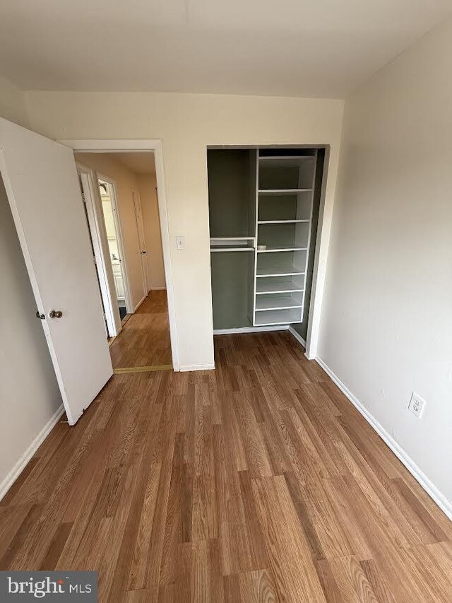 unfurnished bedroom featuring a closet, baseboards, and wood finished floors