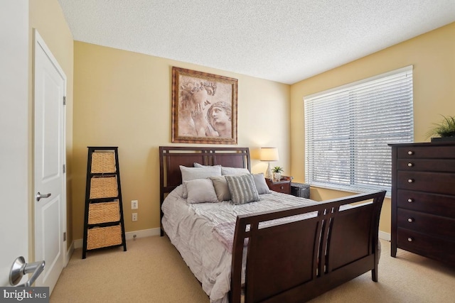 bedroom with light colored carpet, baseboards, and a textured ceiling