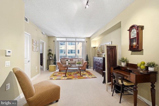 living area with baseboards, light colored carpet, visible vents, and a textured ceiling