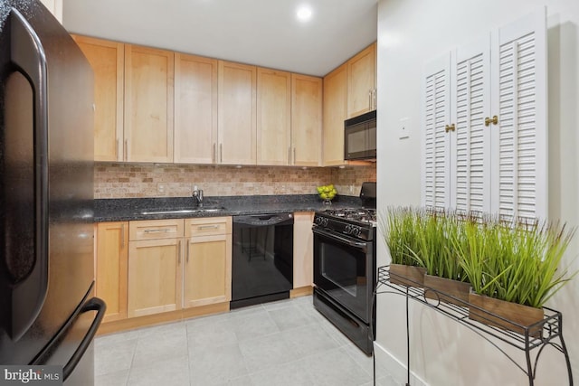 kitchen featuring light tile patterned floors, a sink, light brown cabinetry, black appliances, and backsplash