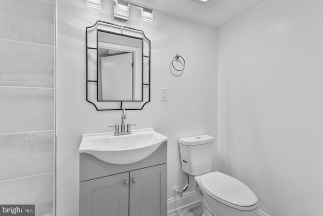 bathroom featuring toilet, vanity, and baseboards