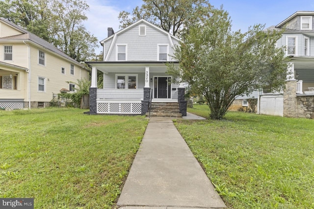 view of front of home featuring a front lawn, covered porch, a gambrel roof, and a chimney