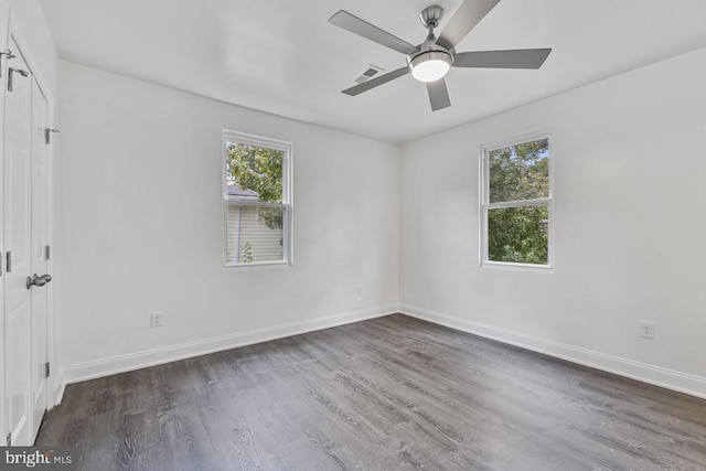 unfurnished room with plenty of natural light, dark wood-type flooring, and baseboards