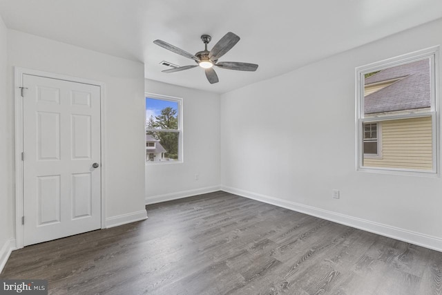 spare room with ceiling fan, visible vents, baseboards, and wood finished floors