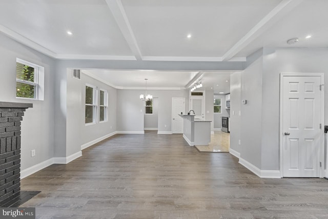 unfurnished living room with visible vents, an inviting chandelier, and wood finished floors