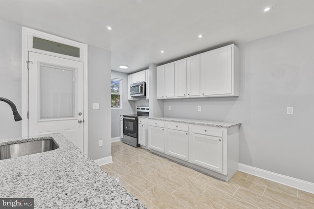 kitchen featuring a sink, stainless steel appliances, light stone countertops, and white cabinets