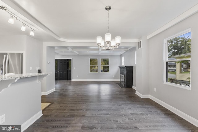 unfurnished living room with plenty of natural light, baseboards, dark wood-type flooring, and visible vents