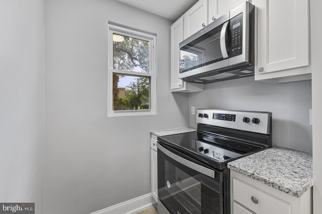 kitchen with light stone counters, stainless steel appliances, baseboards, and white cabinets