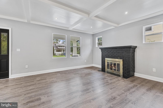 unfurnished living room featuring a brick fireplace, baseboards, beam ceiling, wood finished floors, and coffered ceiling