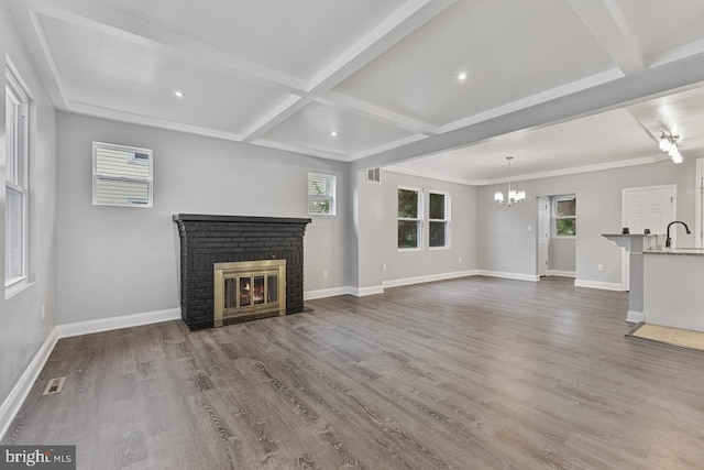 unfurnished living room with baseboards, beam ceiling, wood finished floors, and a fireplace