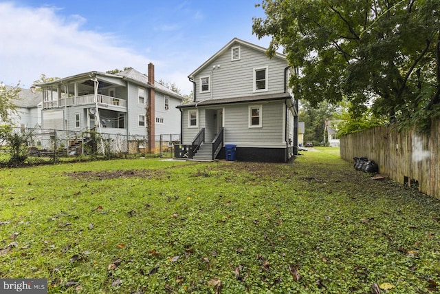 rear view of house with a yard, central AC unit, fence private yard, and entry steps