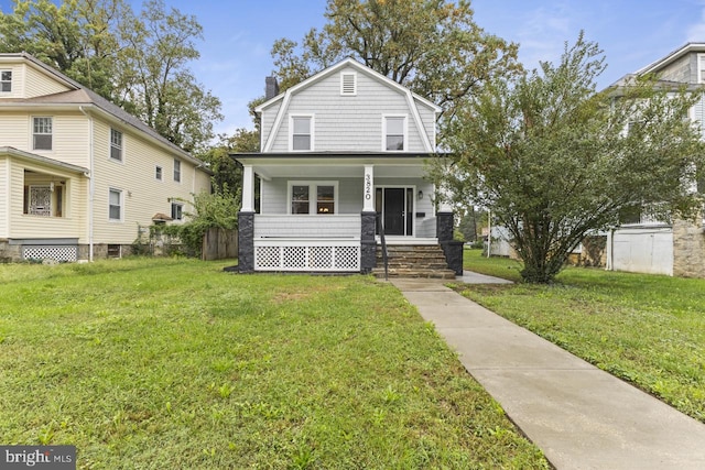 dutch colonial featuring a front yard, covered porch, a gambrel roof, and a chimney