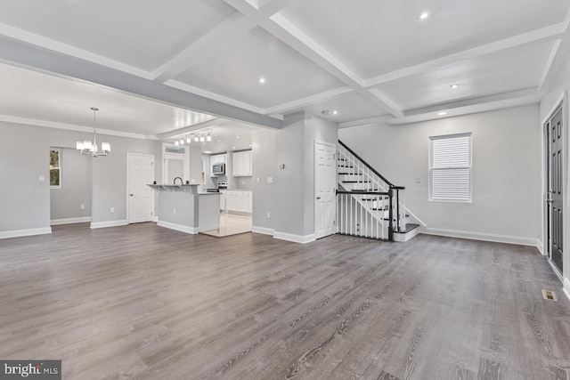 unfurnished living room featuring baseboards, coffered ceiling, dark wood-style flooring, and stairs