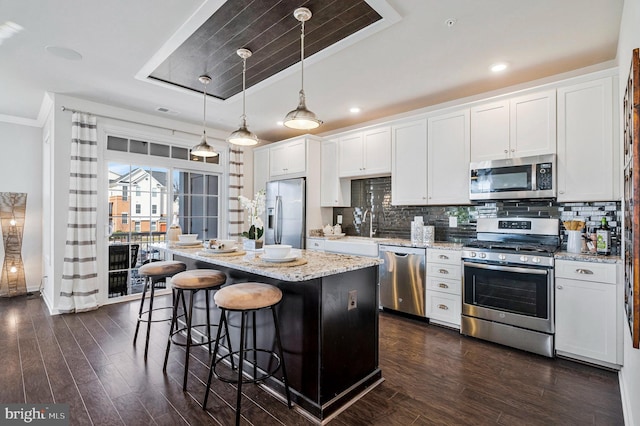 kitchen featuring tasteful backsplash, a breakfast bar, appliances with stainless steel finishes, white cabinetry, and a sink